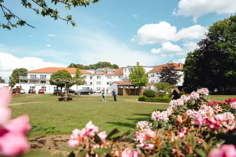Das AuePark Seniorenzentrum hinter einer weitläufigen Gartenanlage mit blühenden Rhododendren.